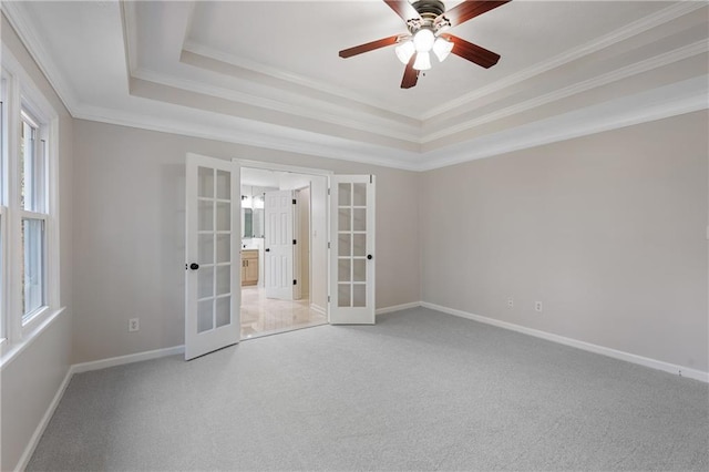 carpeted empty room featuring baseboards, a raised ceiling, a ceiling fan, crown molding, and french doors