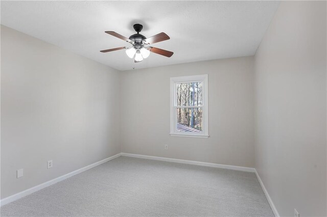 carpeted spare room with a ceiling fan and baseboards