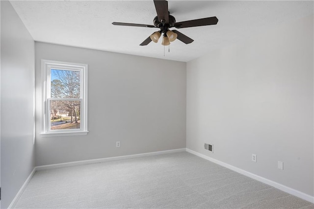 spare room featuring a ceiling fan, light colored carpet, visible vents, and baseboards