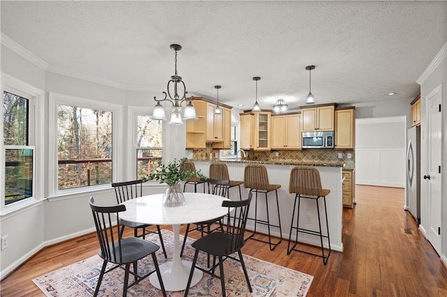 dining room with ornamental molding, wood finished floors, and a healthy amount of sunlight