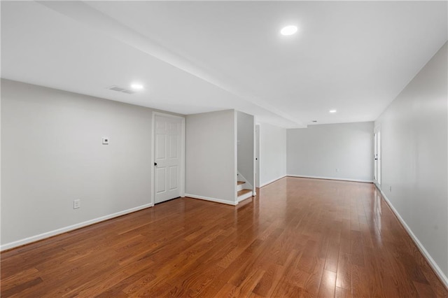 finished below grade area with recessed lighting, wood finished floors, visible vents, baseboards, and stairway