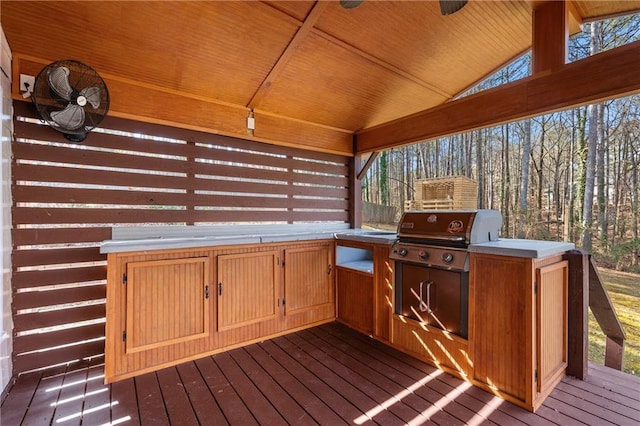 wooden terrace with ceiling fan, area for grilling, and a grill