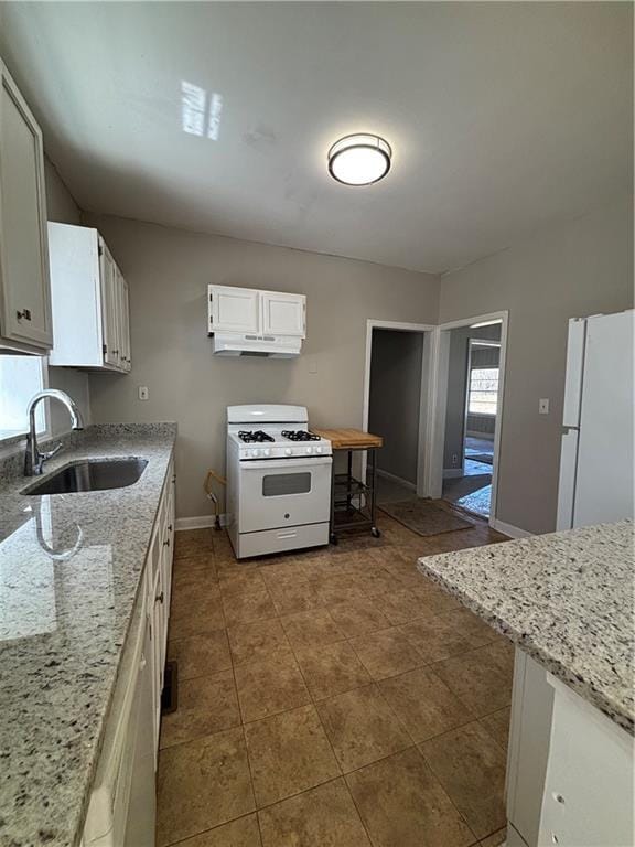 2103 River Rd, Ellenwood, GA 30294 - kitchen with white appliances, under cabinet range hood, white cabinets, light stone counters, and tile patterned flooring