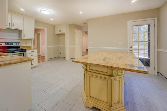 kitchen featuring electric stove, a kitchen island, cream cabinets, backsplash, and recessed lighting