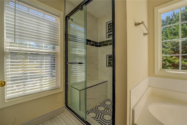 full bathroom featuring a garden tub and a marble finish shower