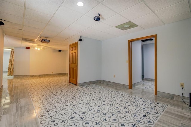 unfurnished room with a drop ceiling and baseboards