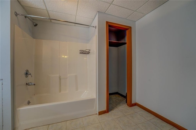 bathroom featuring baseboards, shower / bathing tub combination, a drop ceiling, and tile patterned floors