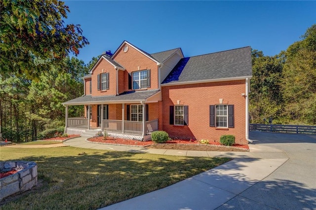 view of front facade featuring a porch, a chimney, a front yard, and brick siding