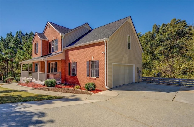 view of side of home with driveway, covered porch, an attached garage, and brick siding