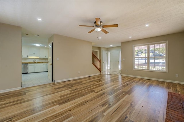 unfurnished living room featuring light wood-type flooring, stairway, baseboards, and recessed lighting