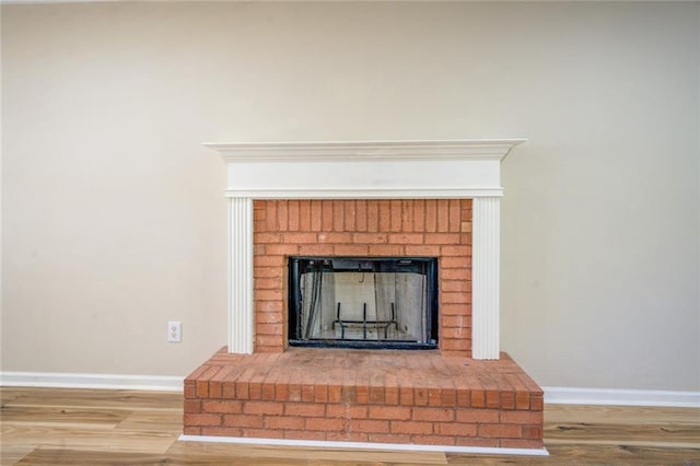 room details with a brick fireplace, baseboards, and wood finished floors