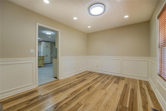 spare room with a wainscoted wall, light wood-style flooring, and recessed lighting