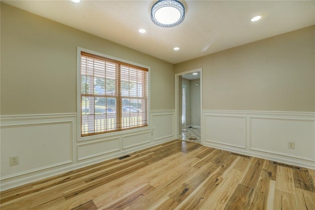 empty room with visible vents, a wainscoted wall, light wood-style flooring, and recessed lighting