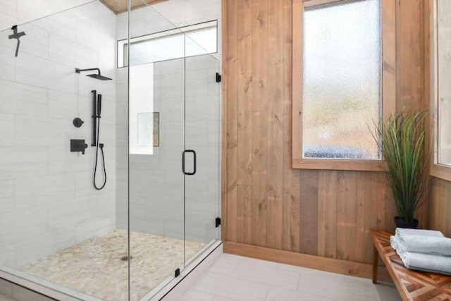 bathroom featuring plenty of natural light, an enclosed shower, tile patterned floors, and wood walls