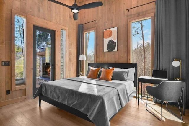 bedroom with multiple windows, access to outside, ceiling fan, and light wood-type flooring