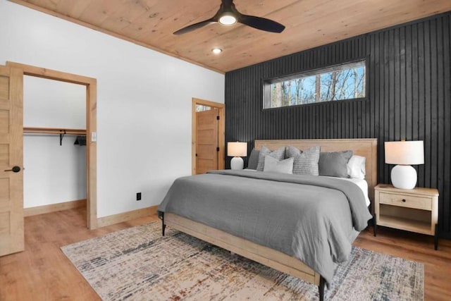 bedroom with ceiling fan, wood-type flooring, a spacious closet, wooden ceiling, and a closet