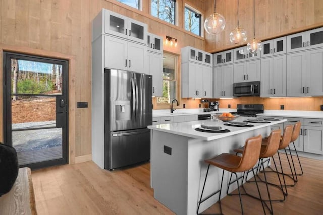 kitchen featuring white cabinetry, hanging light fixtures, stainless steel appliances, and a center island