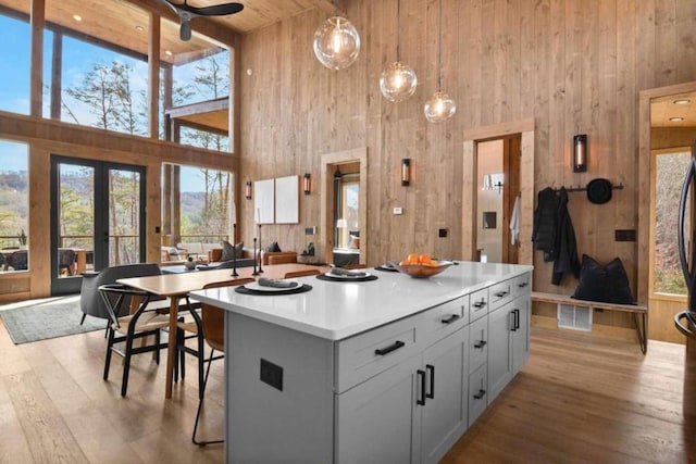 kitchen with wood ceiling, decorative light fixtures, a kitchen breakfast bar, a kitchen island, and light hardwood / wood-style floors