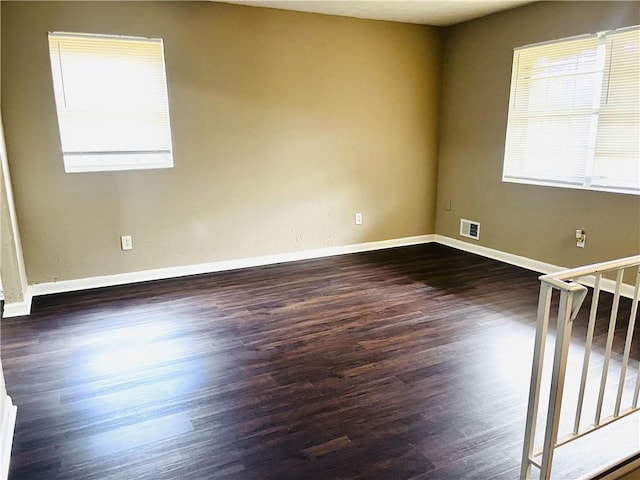 spare room with baseboards, visible vents, stairway, and dark wood-style flooring