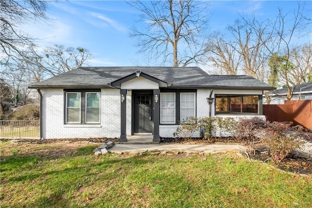 view of front of home featuring a front yard, brick siding, and fence