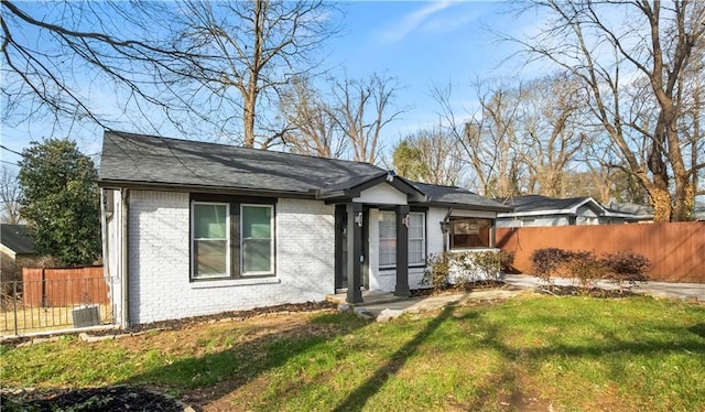 ranch-style house with a front yard, fence, and brick siding