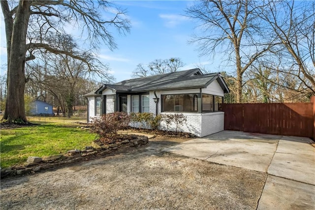 view of front facade with a front yard, brick siding, fence, and driveway