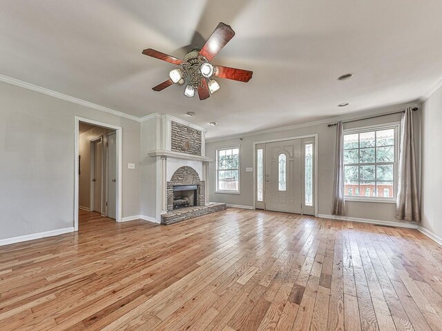 unfurnished living room featuring light hardwood / wood-style floors, ornamental molding, a fireplace, and ceiling fan