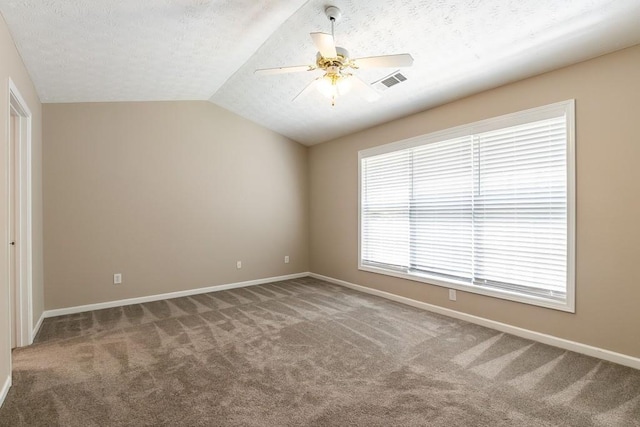 carpeted spare room featuring visible vents, a ceiling fan, vaulted ceiling, a textured ceiling, and baseboards