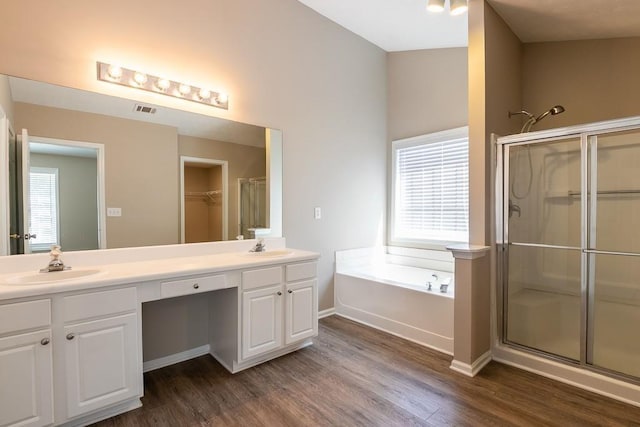 full bath featuring visible vents, a stall shower, a sink, wood finished floors, and a bath