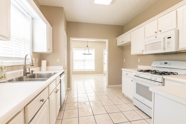 kitchen with white appliances, a sink, white cabinetry, light countertops, and pendant lighting