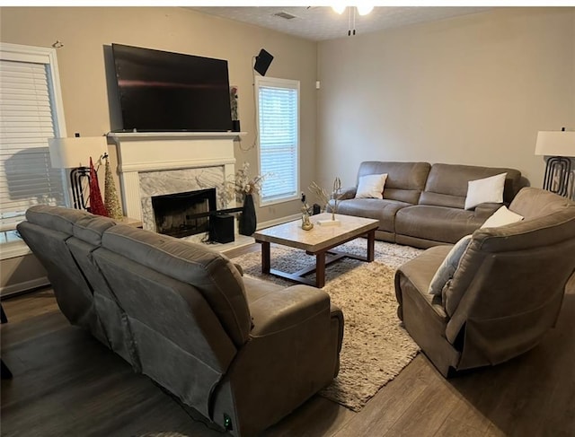 living area with ceiling fan, a fireplace, wood finished floors, visible vents, and baseboards