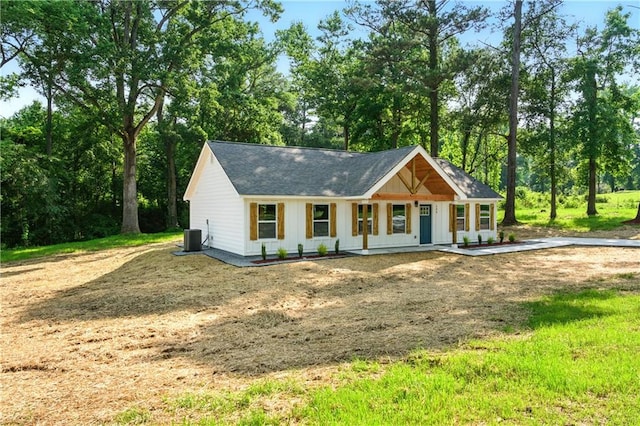 124 Sims Dr, Hiram, GA 30141 - modern farmhouse featuring a porch, central AC, board and batten siding, a shingled roof, and view of wooded area