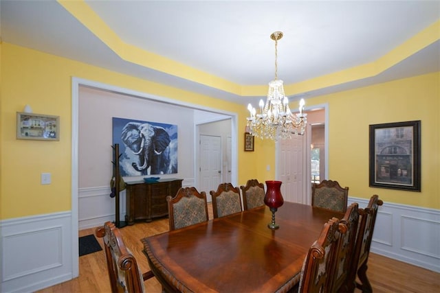 574 Friars Head Dr, Suwanee, GA 30024 - dining space with a chandelier, light wood-style floors, a decorative wall, a wainscoted wall, and a raised ceiling