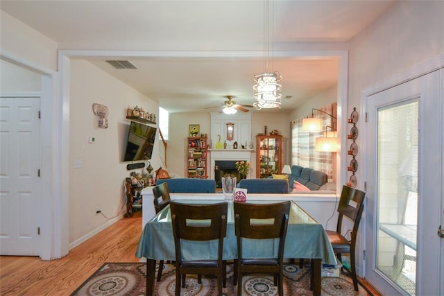 574 Friars Head Dr, Suwanee, GA 30024 - dining space featuring light wood-type flooring, a ceiling fan, healthy amount of natural light, and a fireplace