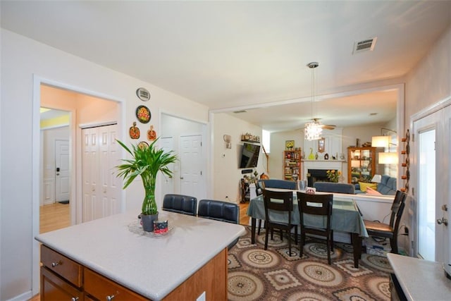 574 Friars Head Dr, Suwanee, GA 30024 - kitchen with brown cabinets, a fireplace, a center island, and light countertops