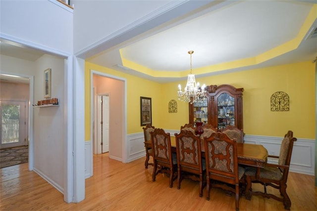 574 Friars Head Dr, Suwanee, GA 30024 - dining room featuring light wood finished floors, a chandelier, a wainscoted wall, a tray ceiling, and a decorative wall