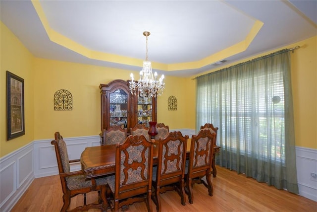 574 Friars Head Dr, Suwanee, GA 30024 - dining room with a chandelier, a tray ceiling, wood finished floors, a decorative wall, and wainscoting