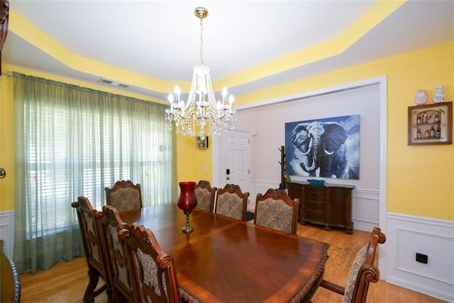 574 Friars Head Dr, Suwanee, GA 30024 - dining space with a chandelier, light wood-style floors, a wainscoted wall, a raised ceiling, and a decorative wall