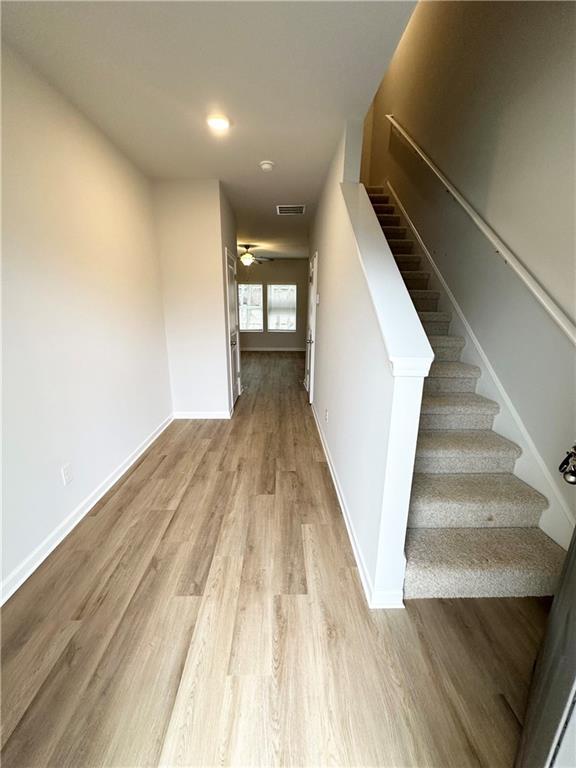 hall featuring stairway, baseboards, visible vents, and wood finished floors