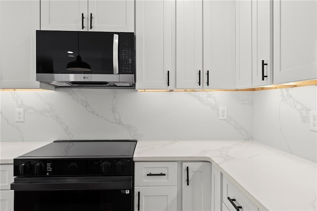 kitchen featuring tasteful backsplash, white cabinetry, light stone countertops, and black electric range