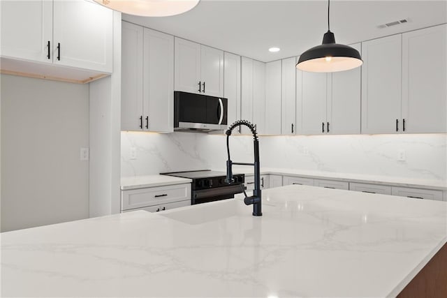 kitchen featuring pendant lighting, white cabinetry, black electric range oven, and light stone counters