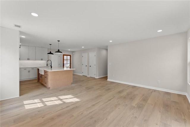 kitchen featuring white cabinetry, a large island, light hardwood / wood-style floors, and pendant lighting