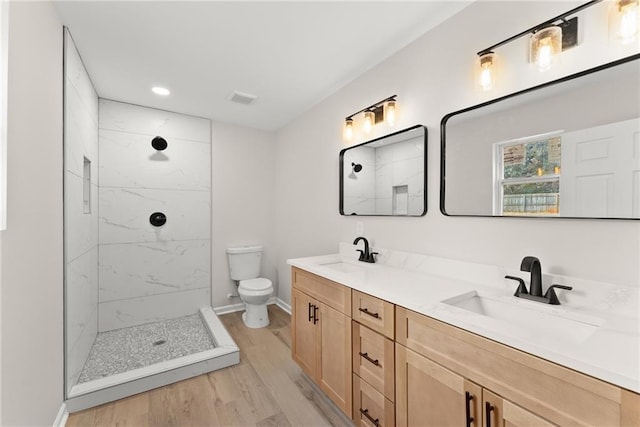 bathroom featuring vanity, hardwood / wood-style floors, toilet, and tiled shower