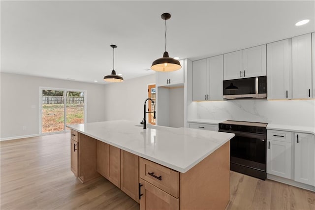 kitchen featuring sink, a center island with sink, pendant lighting, black range with electric stovetop, and white cabinets