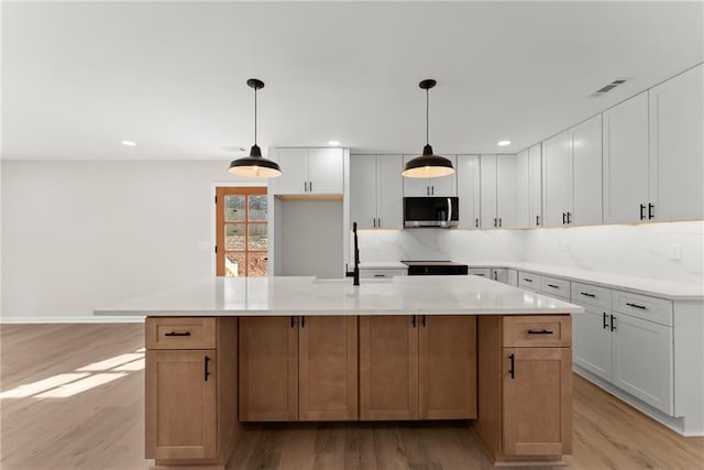 kitchen featuring a large island, pendant lighting, and white cabinets