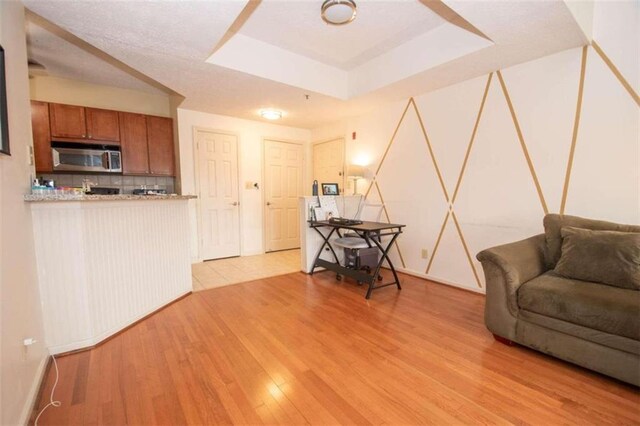 living room featuring a raised ceiling and light wood-type flooring