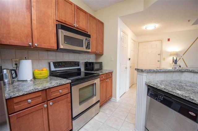 kitchen featuring light stone counters, light tile patterned floors, decorative backsplash, and stainless steel appliances