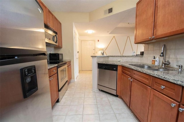 kitchen with sink, light tile patterned flooring, light stone countertops, and appliances with stainless steel finishes