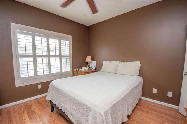 bedroom with multiple windows, light hardwood / wood-style floors, and ceiling fan