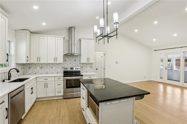 kitchen featuring appliances with stainless steel finishes, vaulted ceiling with beams, a sink, and wall chimney exhaust hood